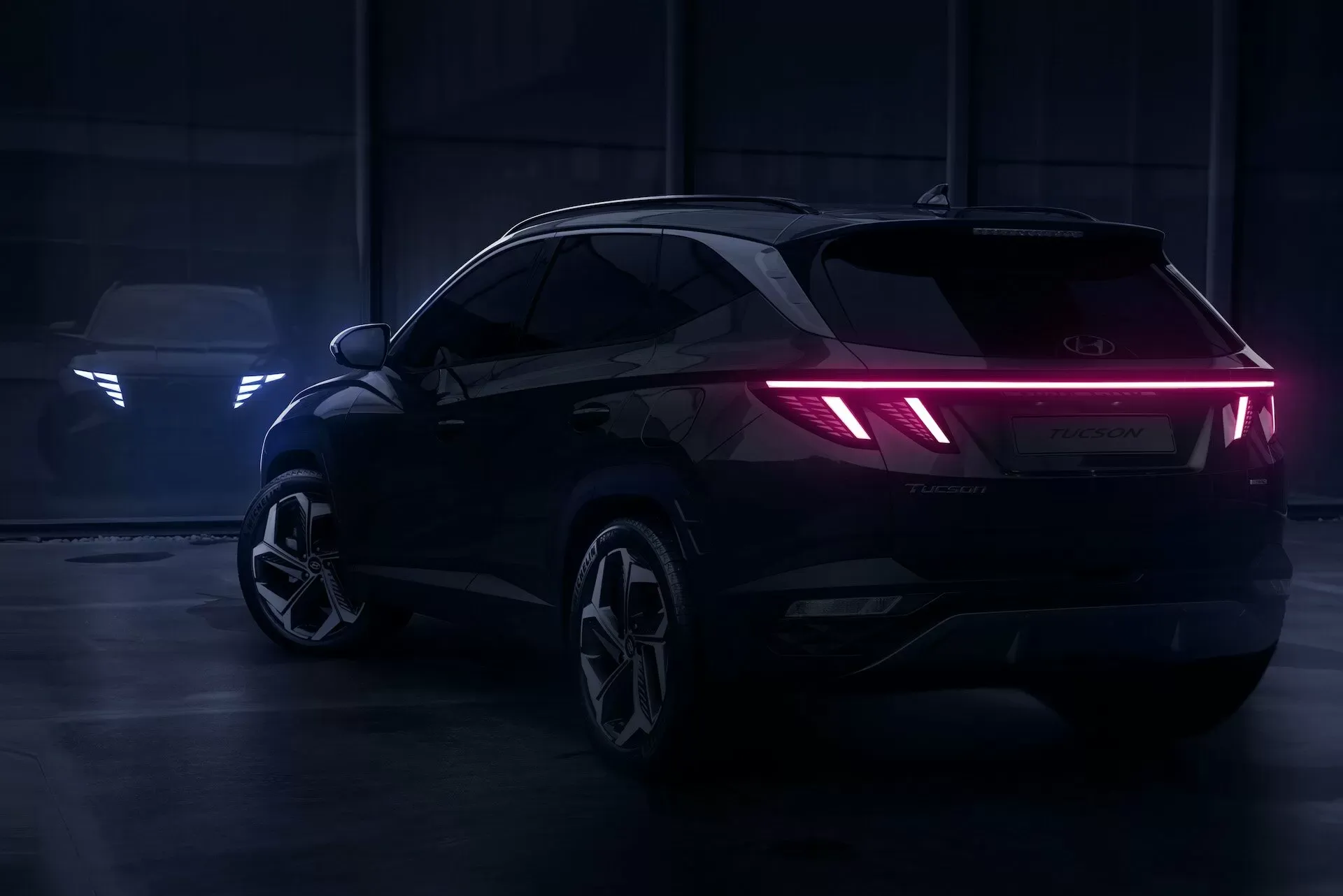 Hyundai Tucson vu de trois quarts arrière dans un garage sombre, feux arrière allumés