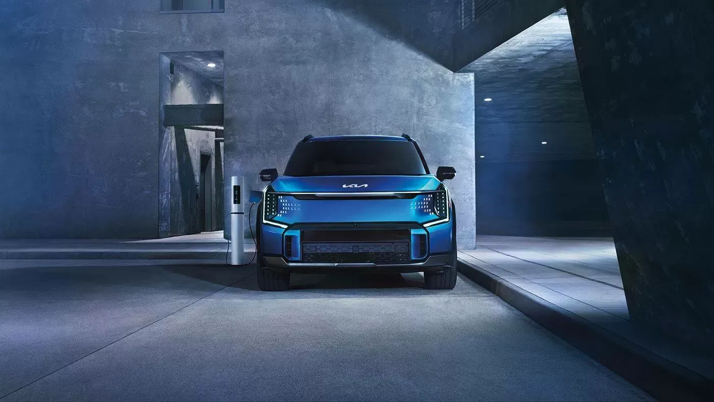 Kia EV9 bleue branchée à une borne de recharge dans un stationnement de béton